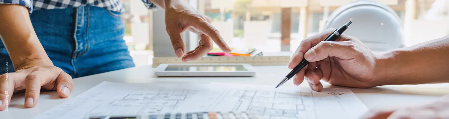 Plan liegt auf Tisch und Person zeichnet